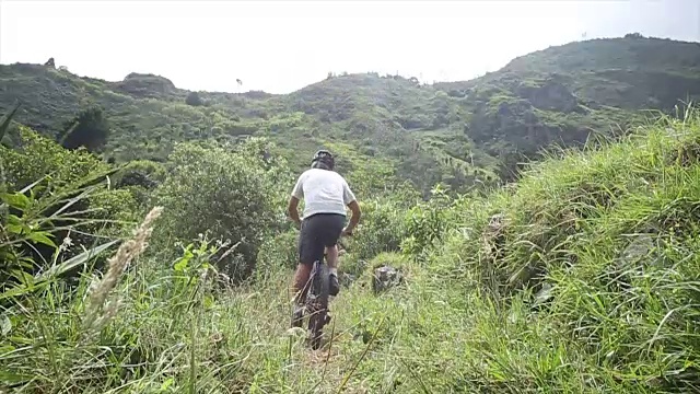 男人沿着森林小径骑自行车，上坡视频素材