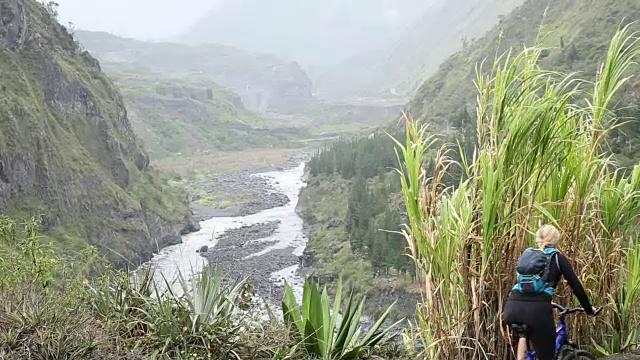 女子停在自行车旁，低头望向河谷视频素材