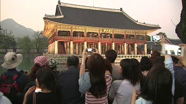 一群人在京会馆(韩国国宝224)和京福宫池塘(朝鲜王朝皇宫)拍照留影视频素材