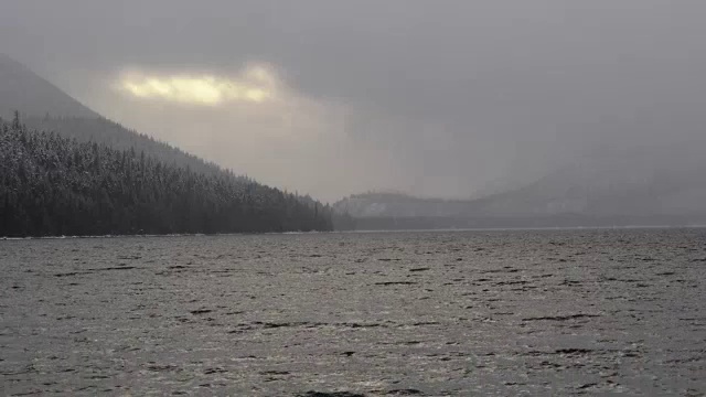 长焦拍摄的山湖在冬天与暗灰色的云和降雪。视频素材