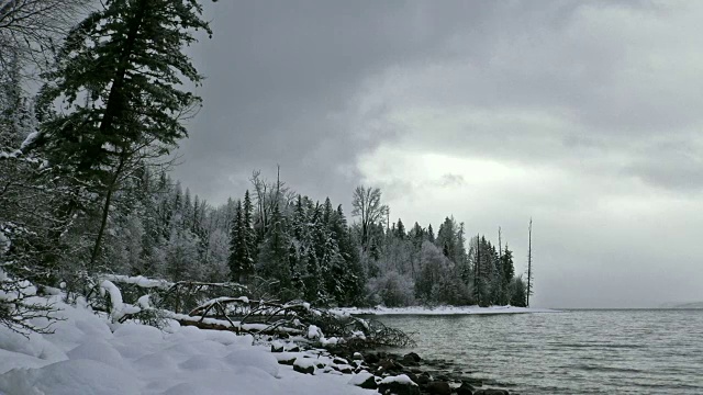 潘右宽拍摄的雪覆盖的海岸线上的山湖在冬天与暗灰色的云。视频素材