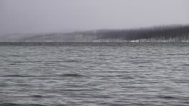 长焦拍摄的山湖在冬天与雪覆盖的海岸线在远处和暗灰色的云。视频素材