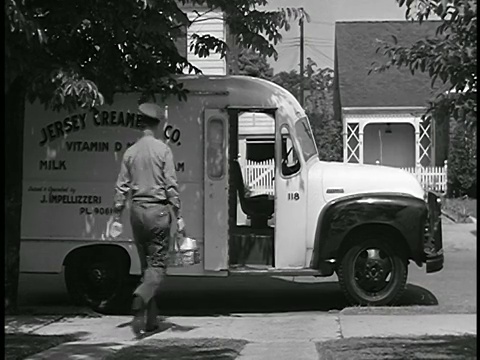 1948年送牛奶的人上了卡车，开车离开了郊区的街道/工业区视频素材