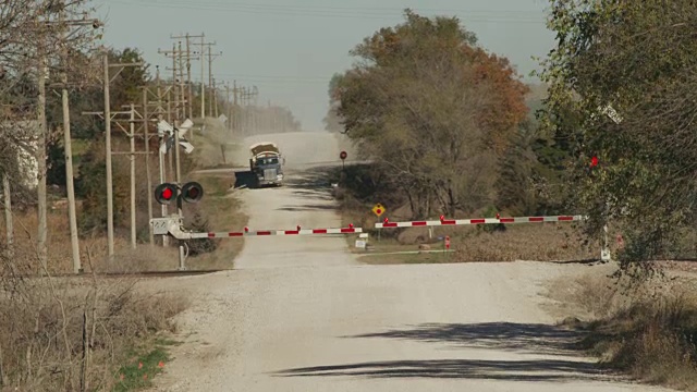 圣塔菲和BNSF的火车拉着油车在一个铁路十字路口的农村公路上赛跑。视频素材