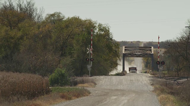 在秋季收获季节，几辆农用和运粮的卡车在尘土飞扬的乡村道路上行驶。视频素材