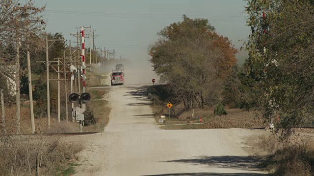 一辆农用卡车在铁路交叉处的乡间砾石路上行驶。视频素材