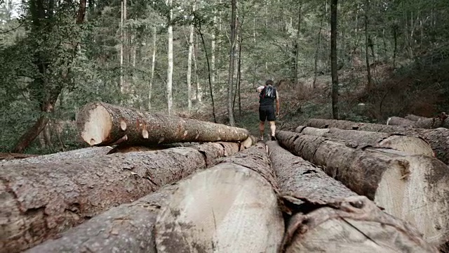 SLO MO DS赤脚跑者在森林里跑过一堆木头视频素材