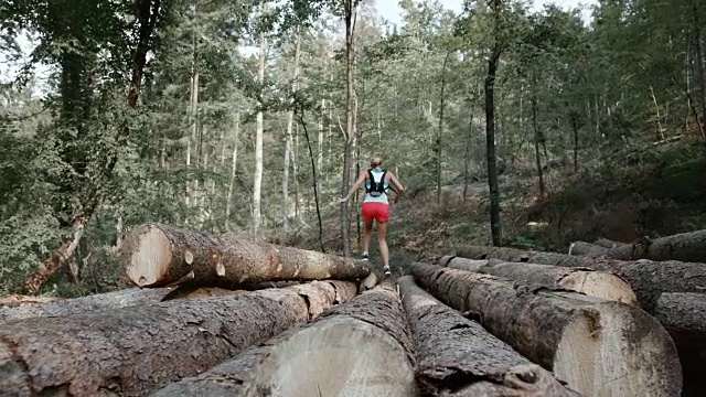 一个女人在森林里跑过一堆木头视频素材