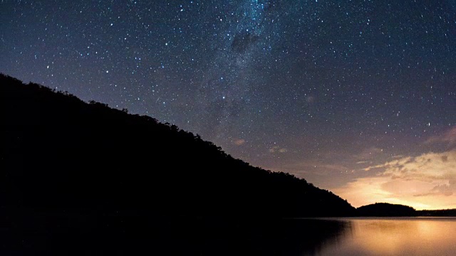 在夜晚，线性的和泛型的时间流逝，一座山的剪影和一个水坝与银河系和戏剧性的雷暴视频素材