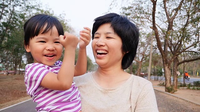 妈妈抱着她的女儿在公园里视频素材