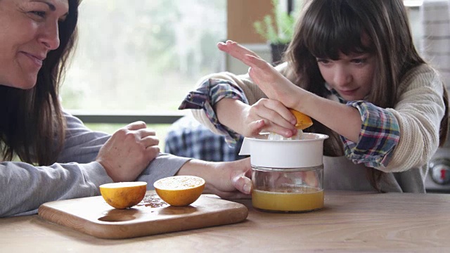 妈妈在家里帮助小女孩做橙汁视频素材