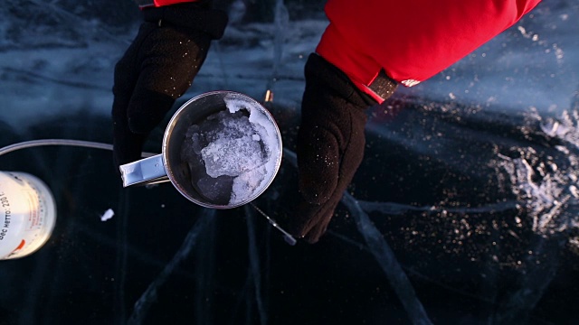 人们用煤气炉将雪中的水烧开。视频素材