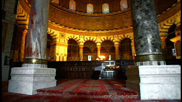 从圆顶清真寺(Dome of the Rock mosque)的天花板向跪在耶路撒冷祈祷的穆斯林妇女拍摄的低角度倾斜摄影车视频素材