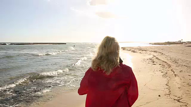 女人推着自行车沿着空荡荡的海滩，旁边是冲浪板视频素材