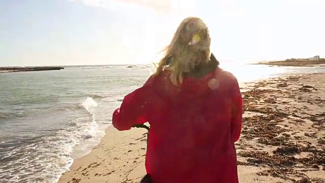 女人推着自行车沿着空荡荡的海滩，旁边是冲浪板视频素材