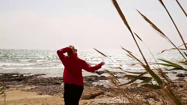 在刮风的日子，女人走过空荡荡的海滩视频素材