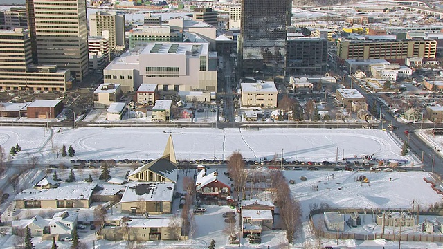 美国阿拉斯加州德莱尼公园/安克雷奇市中心的建筑和雪橇队的WS AERIAL DS ZI视图视频素材