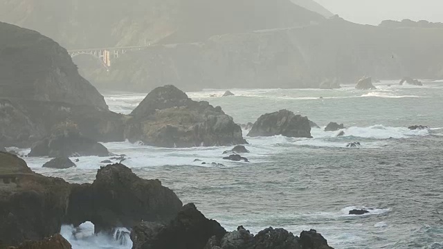 大苏尔的岩石海岸线，海浪拍打着海岸，阳光照耀着。视频素材