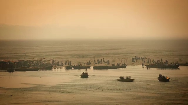 清晨橘色的天空是大壶节(Kumbh Mela)河岸上朝圣者活动的背景视频素材