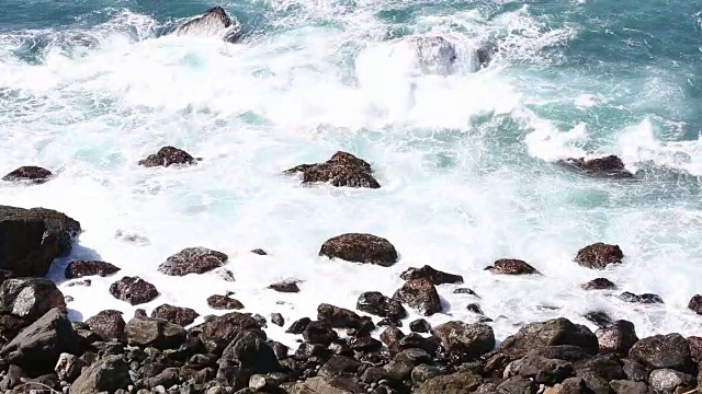 大苏尔的岩石海岸线，海浪拍打着海岸，阳光照耀着。视频素材