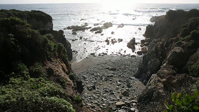 大苏尔的岩石海岸线，海浪拍打着海岸，阳光照耀着。视频素材