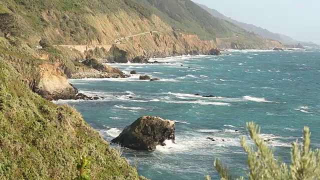 大苏尔的岩石海岸线，海浪拍打着海岸，阳光照耀着。视频素材