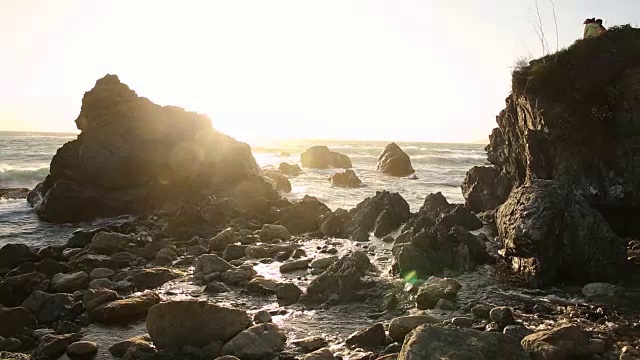 大苏尔的岩石海岸线，海浪拍打着海岸，阳光照耀着。视频素材