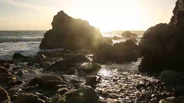 大苏尔的岩石海岸线，海浪拍打着海岸，阳光照耀着。视频素材