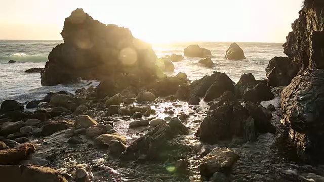 大苏尔的岩石海岸线，海浪拍打着海岸，阳光照耀着。视频素材