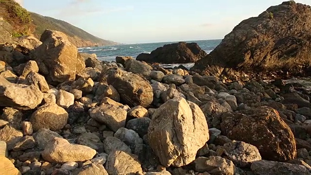 大苏尔的岩石海岸线，海浪拍打着海岸，阳光照耀着。视频素材