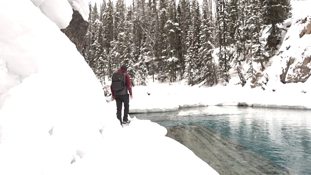 徒步旅行者沿着河边的积雪小径行走视频素材