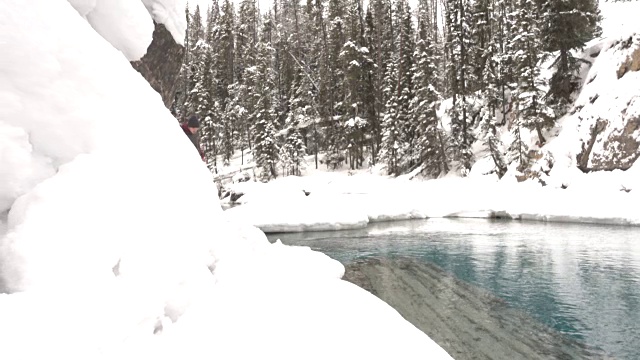 徒步旅行者沿着河边的积雪小径行走视频素材