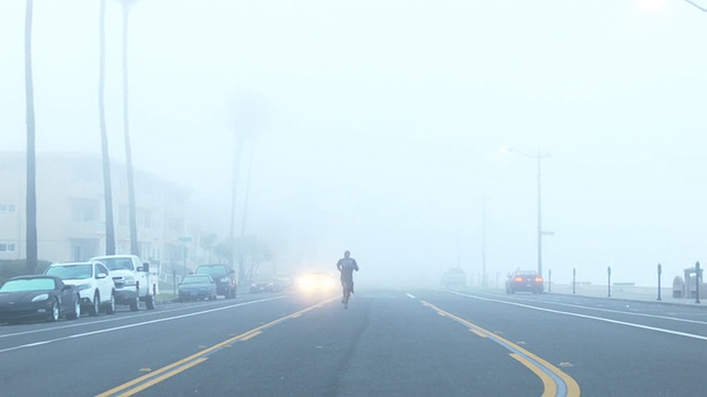 一个年轻人在海滩边一个住宅区的街道上跑步。视频素材