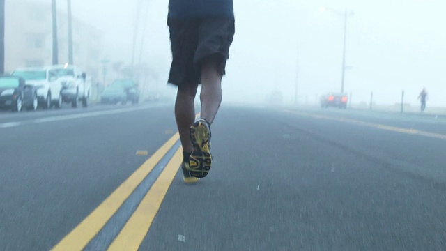 一个年轻人在海滩边一个住宅区的街道上跑步。视频素材