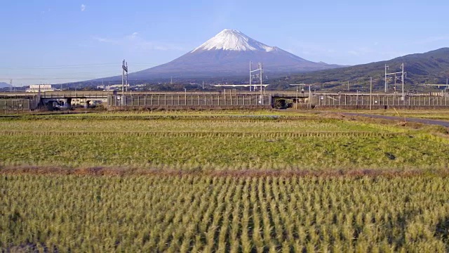 日本，本州，富士山，新干线子弹列车通过收获的稻田下的积雪覆盖的火山视频素材