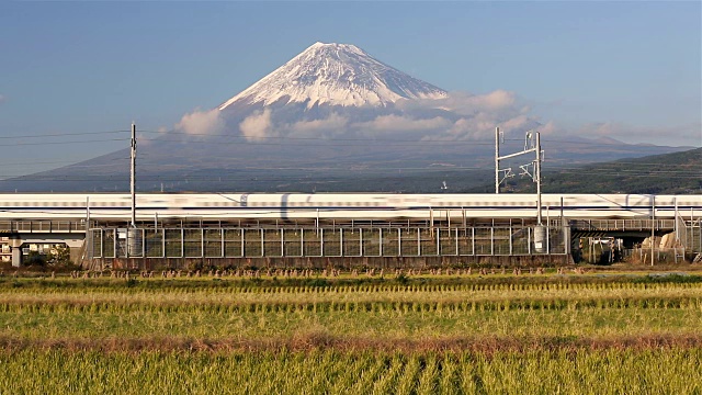 日本，本州，富士山，新干线子弹列车通过收获的稻田下的积雪覆盖的火山视频素材