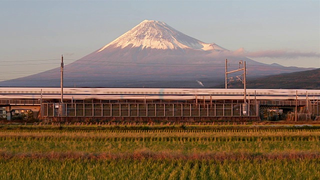 日本，本州，富士山，新干线子弹列车通过收获的稻田下的积雪覆盖的火山视频素材