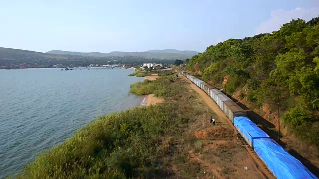 一架无人机飞过一列沿着坦尼喀湖海岸线行驶的货运列车。视频素材