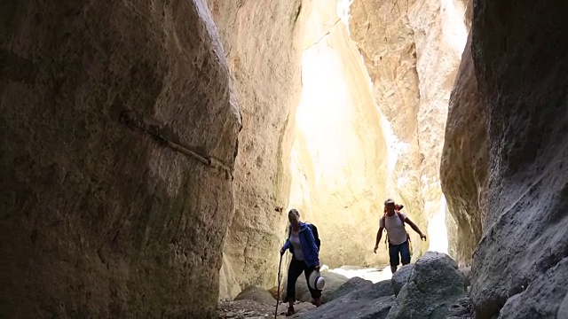 徒步旅行的夫妇探索深深的峡谷，与头顶的木楔石视频素材