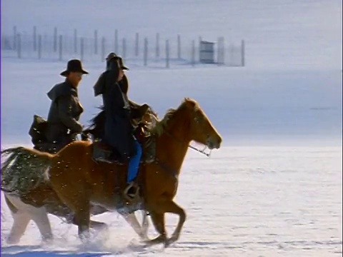 慢镜头PAN男人+女人骑着马在深雪平原上飞驰/ Silverthorne, CO视频素材