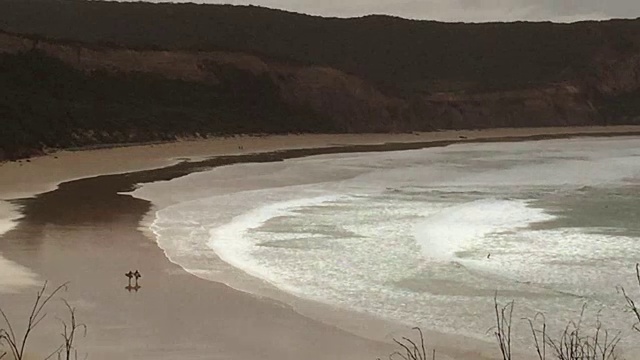 两个冲浪者在冲浪海岸的海滩上散步视频素材