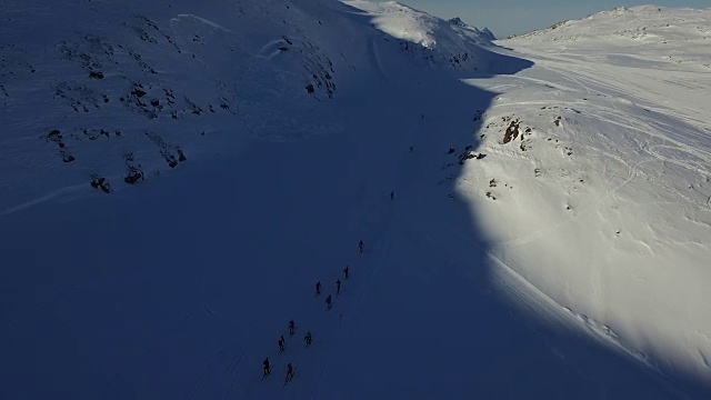 一组滑雪运动员从后面跑上山的无人机镜头视频下载