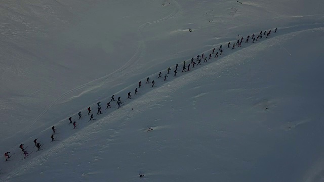 近距离的无人机拍摄了一群滑雪者向山上奔跑的镜头视频下载