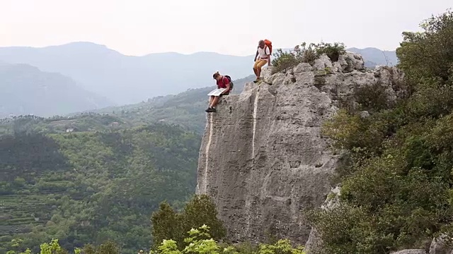 父子俩停了下来，徒步前往山谷之上的崖顶视频素材