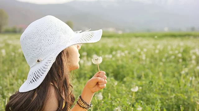 慢动作女孩用蒲公英种子旋转视频素材