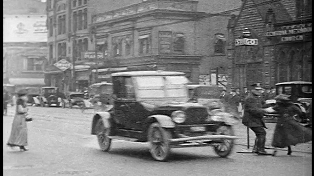 1920年，在城市街道上，交警从迎面而来的汽车的路径上抓过一名过马路的妇女视频素材