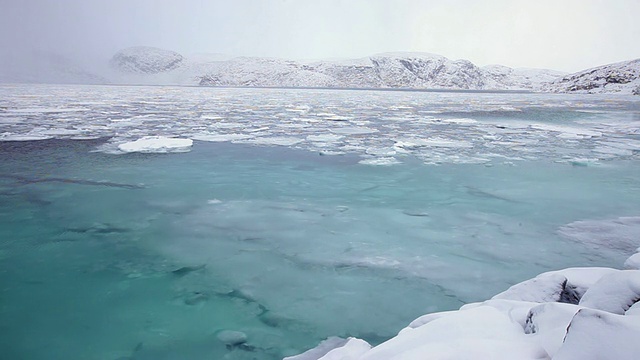 水和冰在流动，周围是积雪覆盖的河岸视频素材