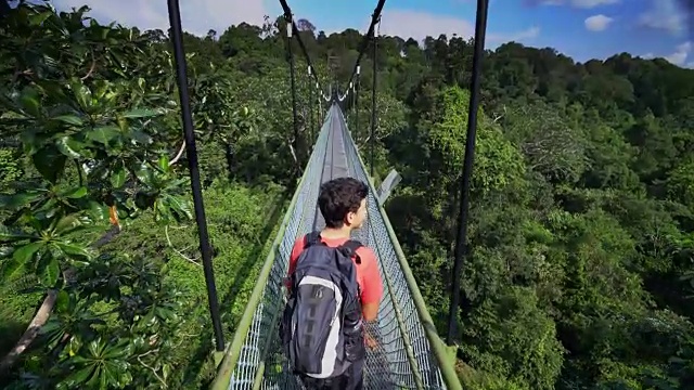 一个十几岁的男孩在森林上的桥上行走视频素材