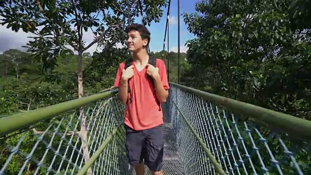 一个十几岁的男孩在雨林里背包旅行视频素材