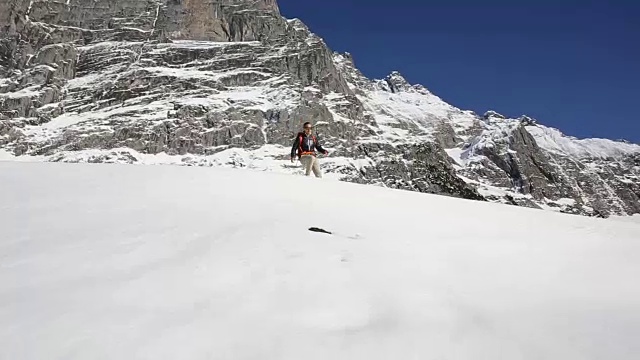 男性徒步者走下陡峭的雪坡，然后喝小溪里的水视频素材